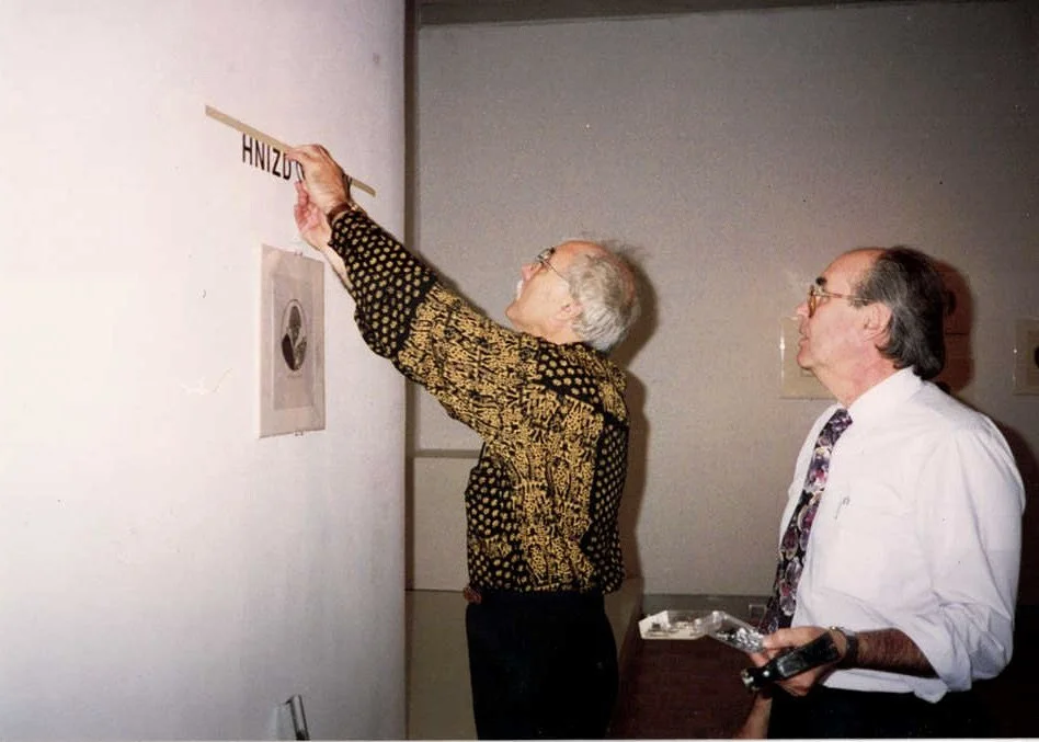 Two men hanging a Jacques Hnizdovsky exhibition sign on the gallery wall