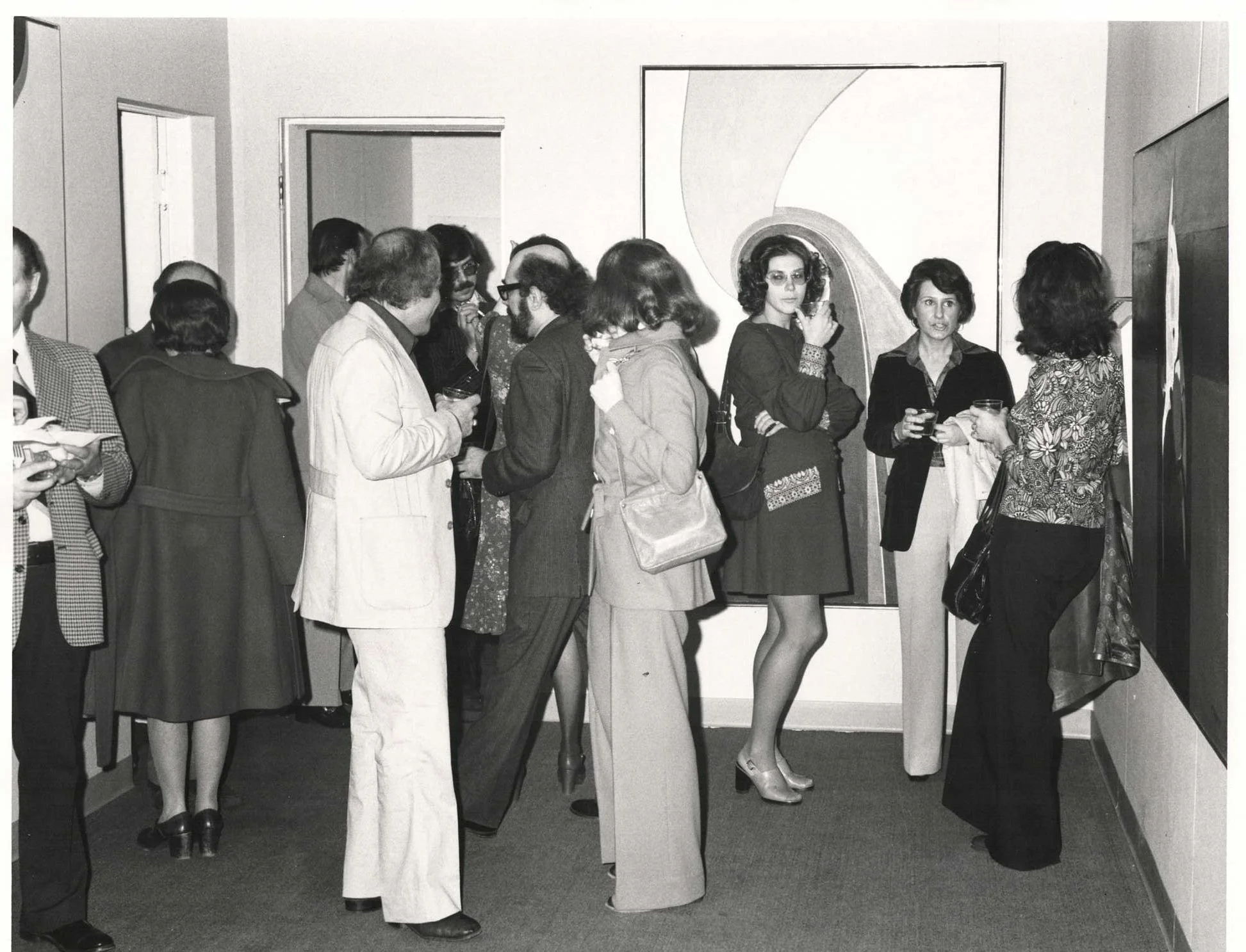 Guests mingling at a UIMA opening reception in the 1970s, in front of an abstract painting