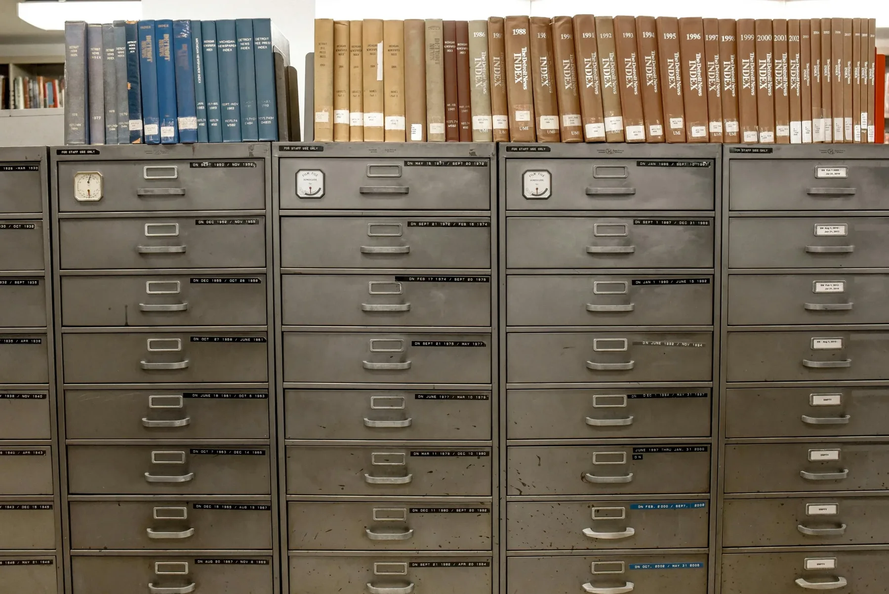 Rows of labeled archival filing cabinets and bound periodical indexes in a research library