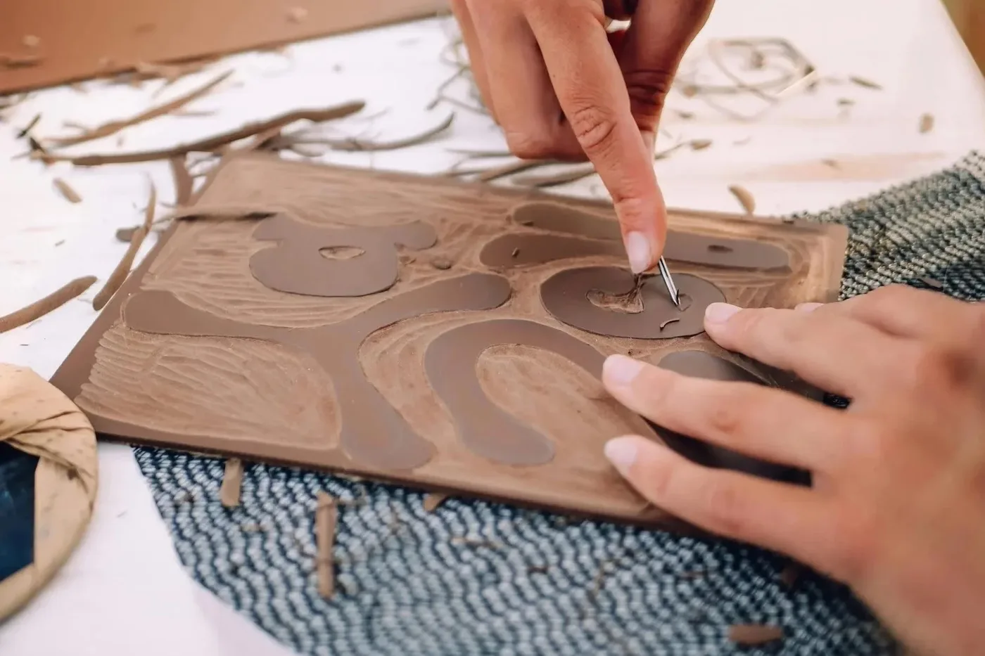 Close-up of hands using a carving tool on a linoleum printing block during an artist-led workshop