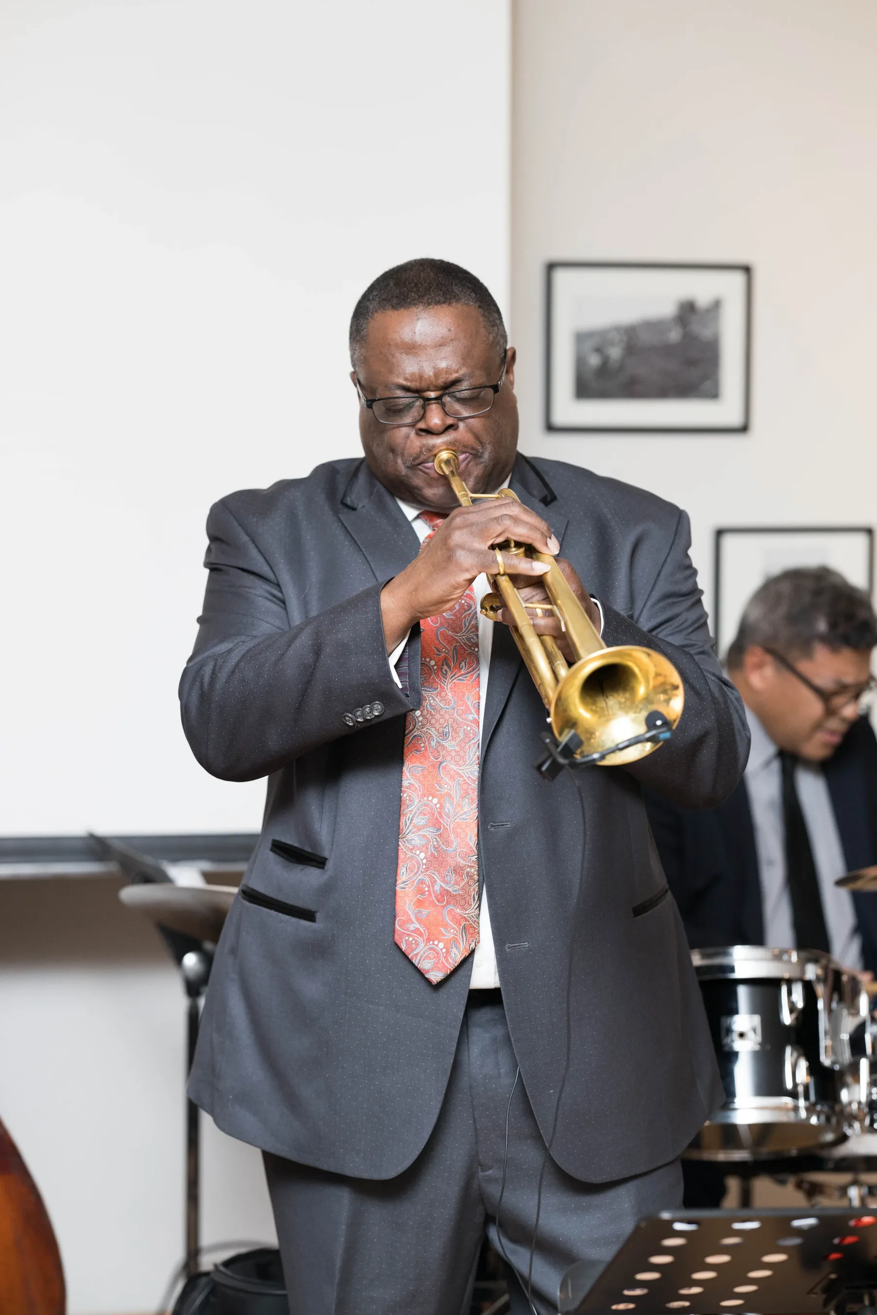 A trumpet player performing at a UIMA concert, drummer visible behind him