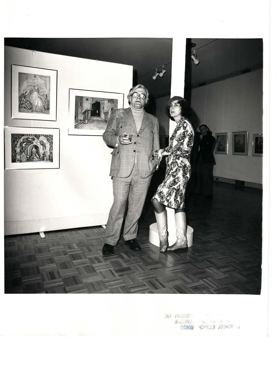 A man in the gallery in front of a 1957 painting signed Hnizdovsky, depicting a crowd viewed from above
