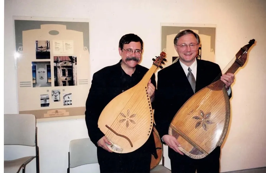 A couple at a gallery opening reception, standing beside framed works on paper