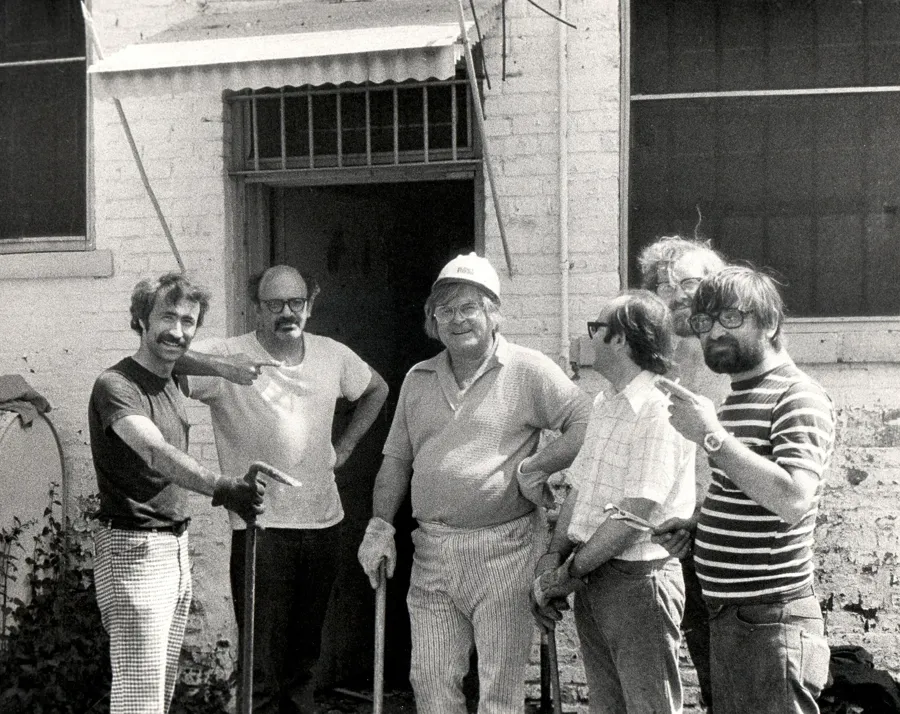 Early UIMA volunteers, one in a hard hat, gathered outside the building during renovation work