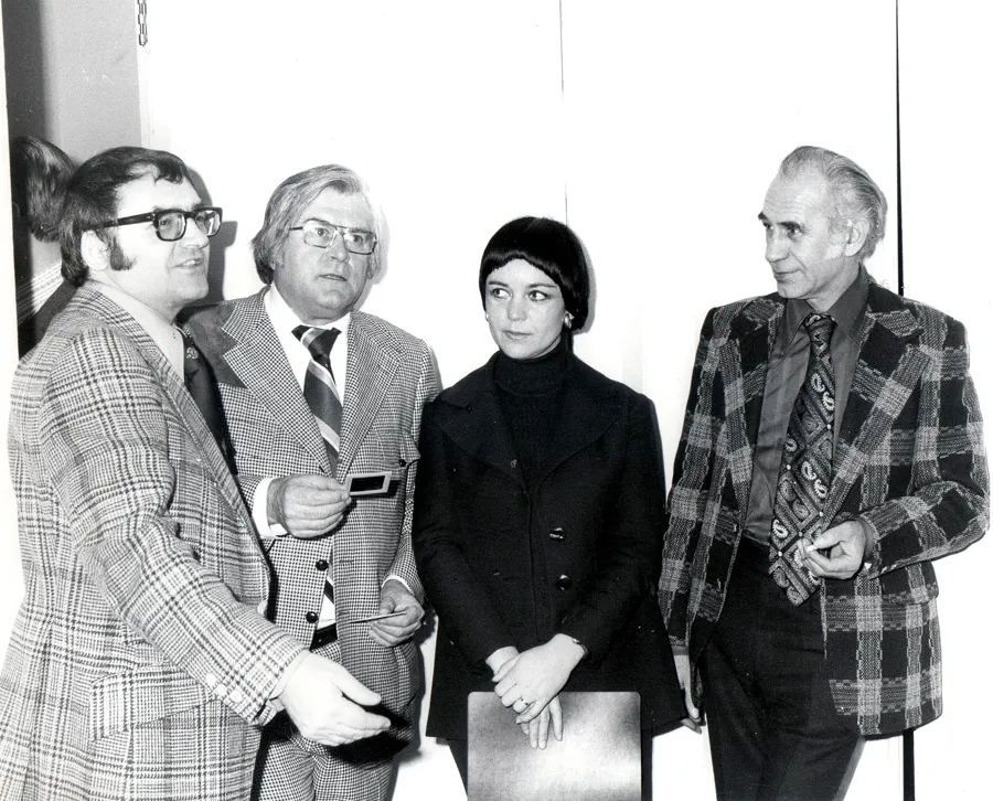 A group of four at a gallery reception in front of a large painted canvas